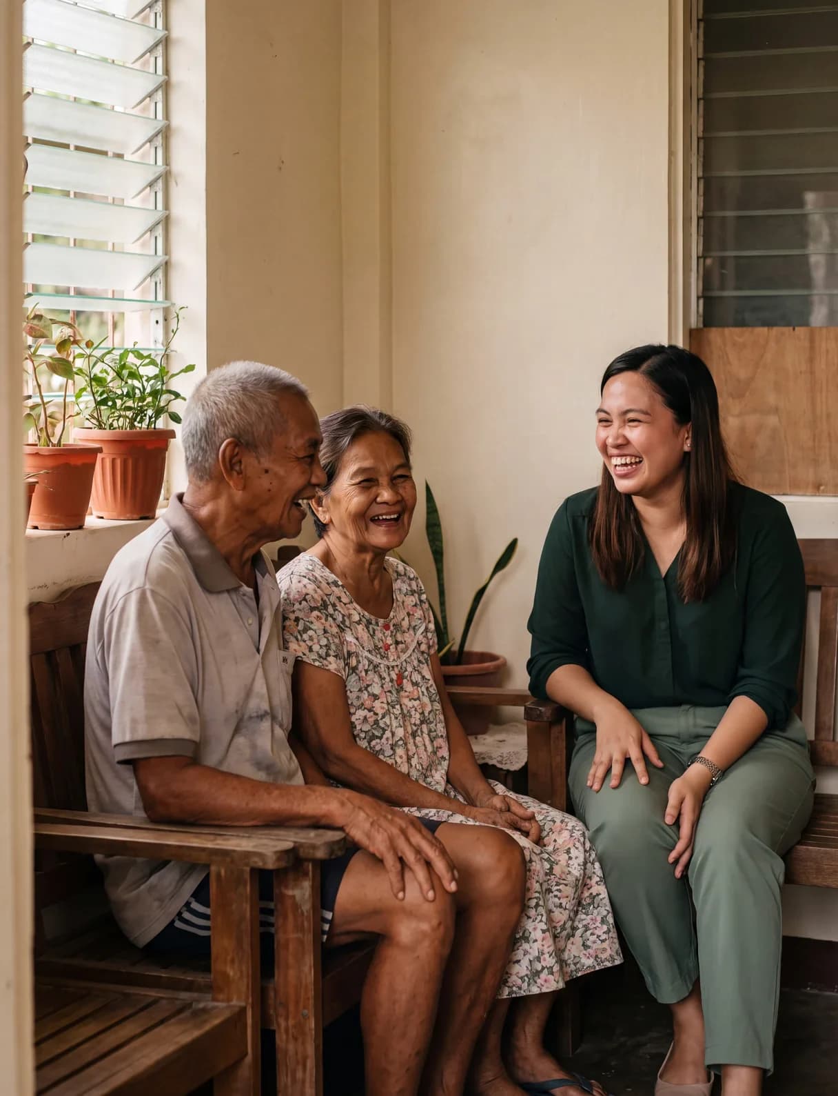A local coordinator sitting and laughing with an older couple on the shaded porch of their home in Cebu.